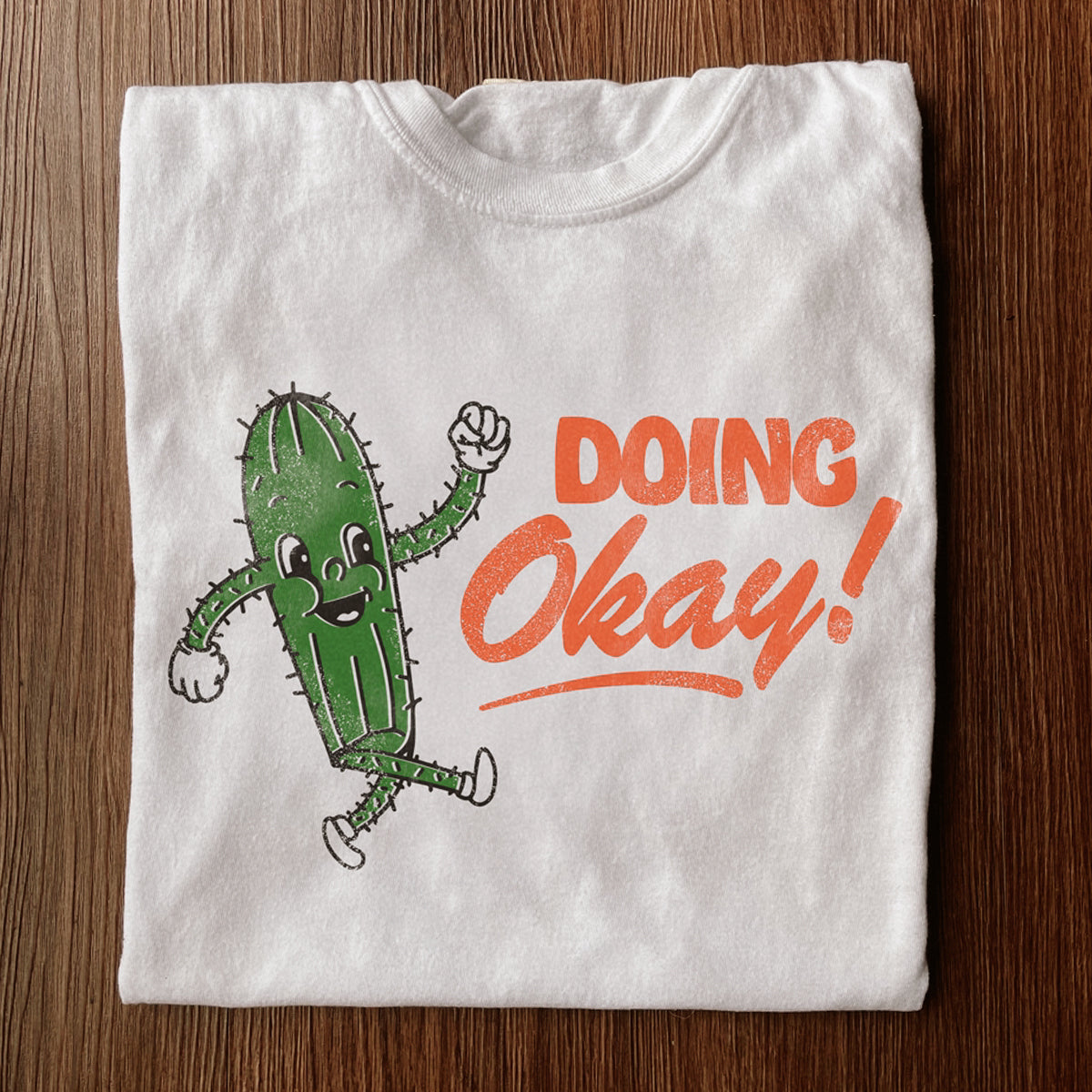 White shirt that says Doing Okay with a smiley cactus walking