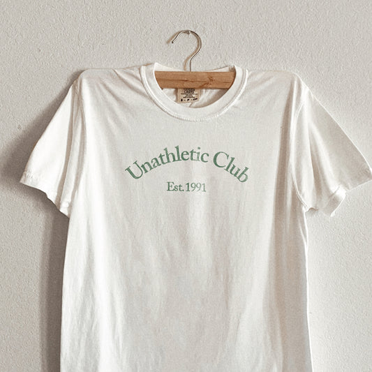 White shirt that says Unathletic Club Established 1991 in green 